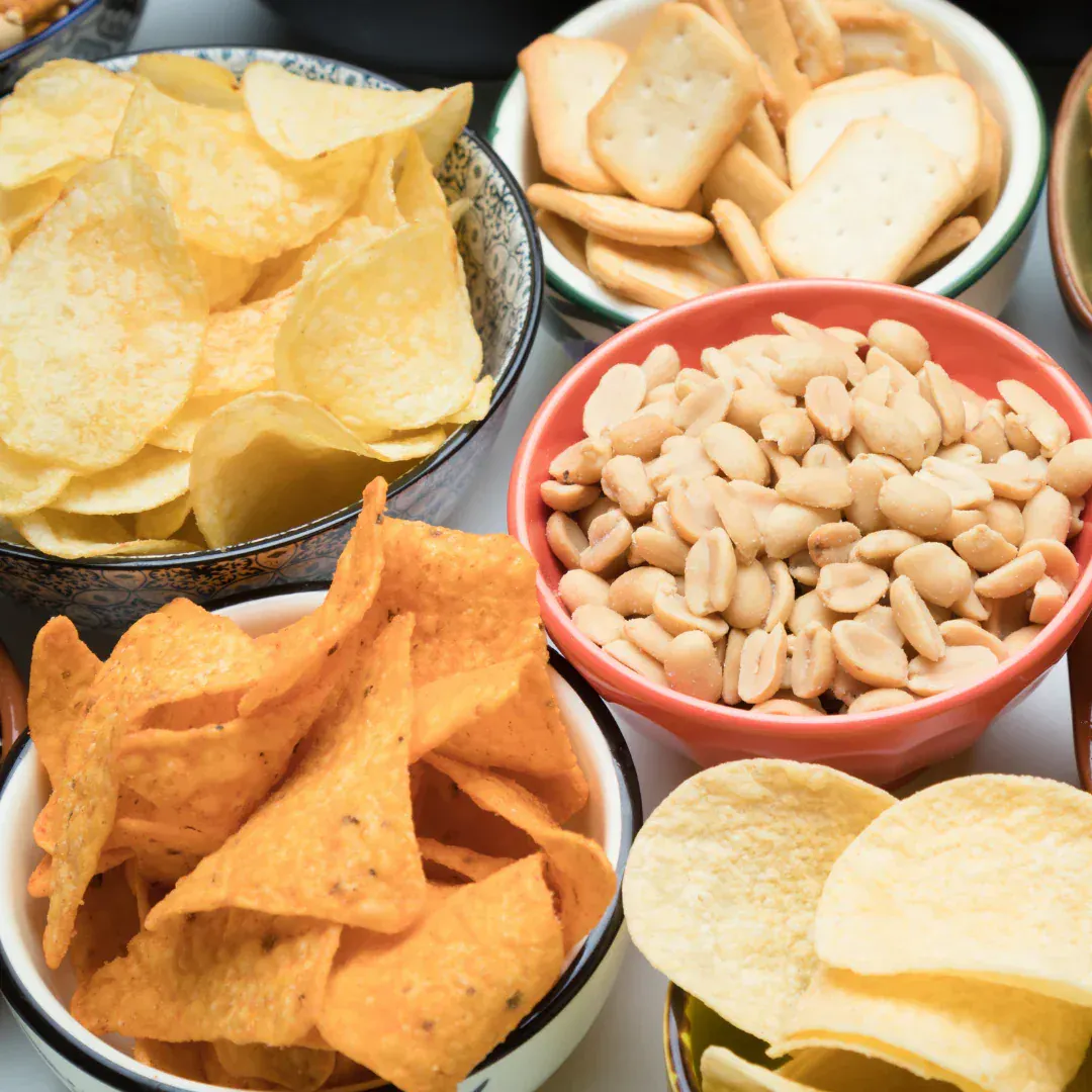 An assortment of salty snacks in different bowls.