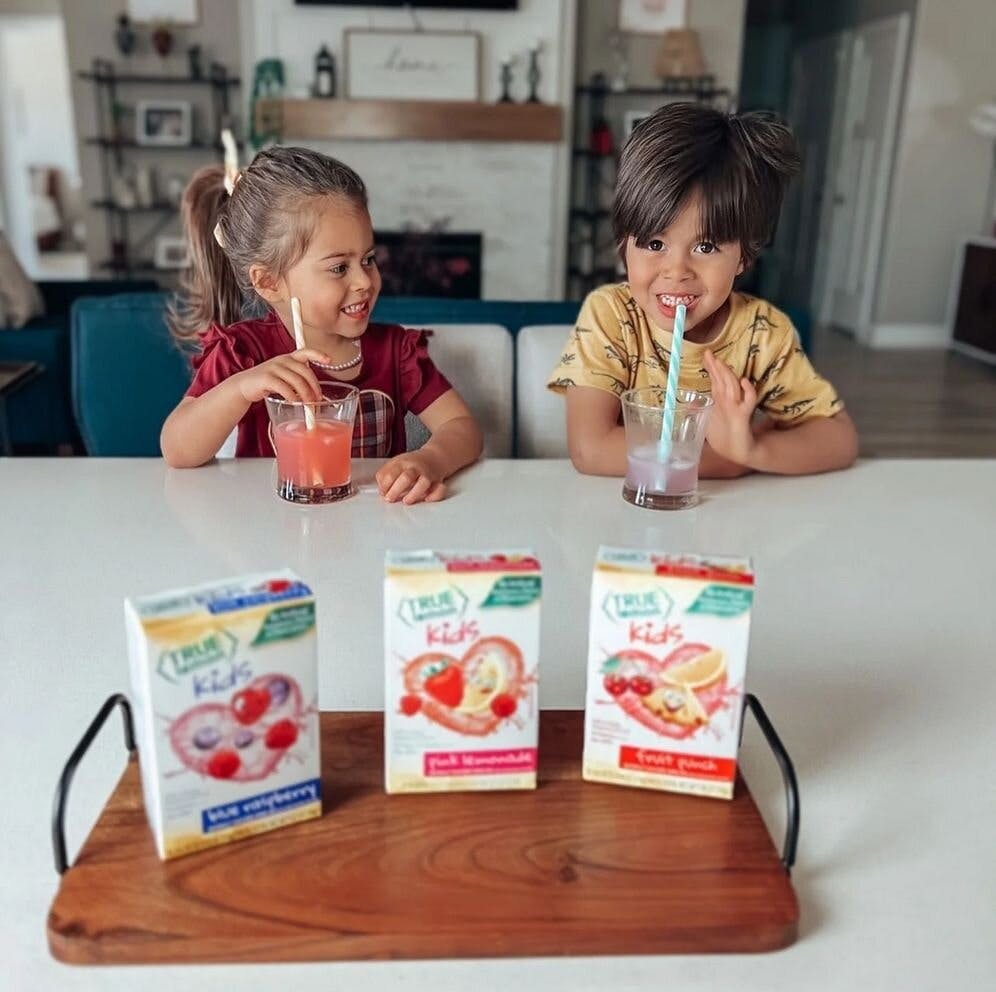 Two kids sitting at a counter drinking True Lemon.