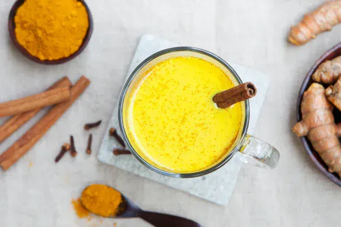 A cup of True Citrus Turmeric Tea next to spices and ginger.