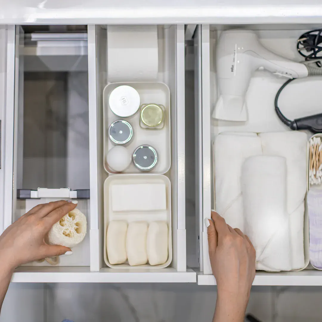 A woman organizing a bathroom drawer.