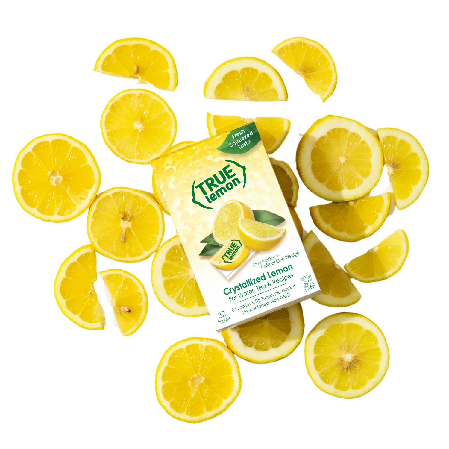 A pitcher is pouring water into a glass. There is a box of True Lemon Fruit Infusions on the table.