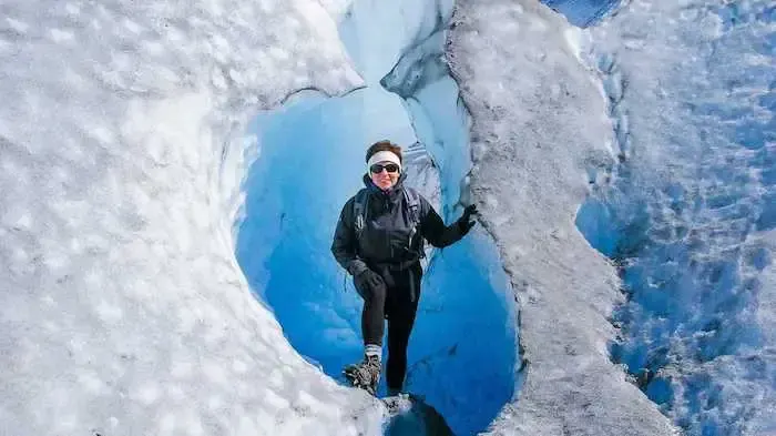 Claudia is in cold weather gear standing inside a glacier.