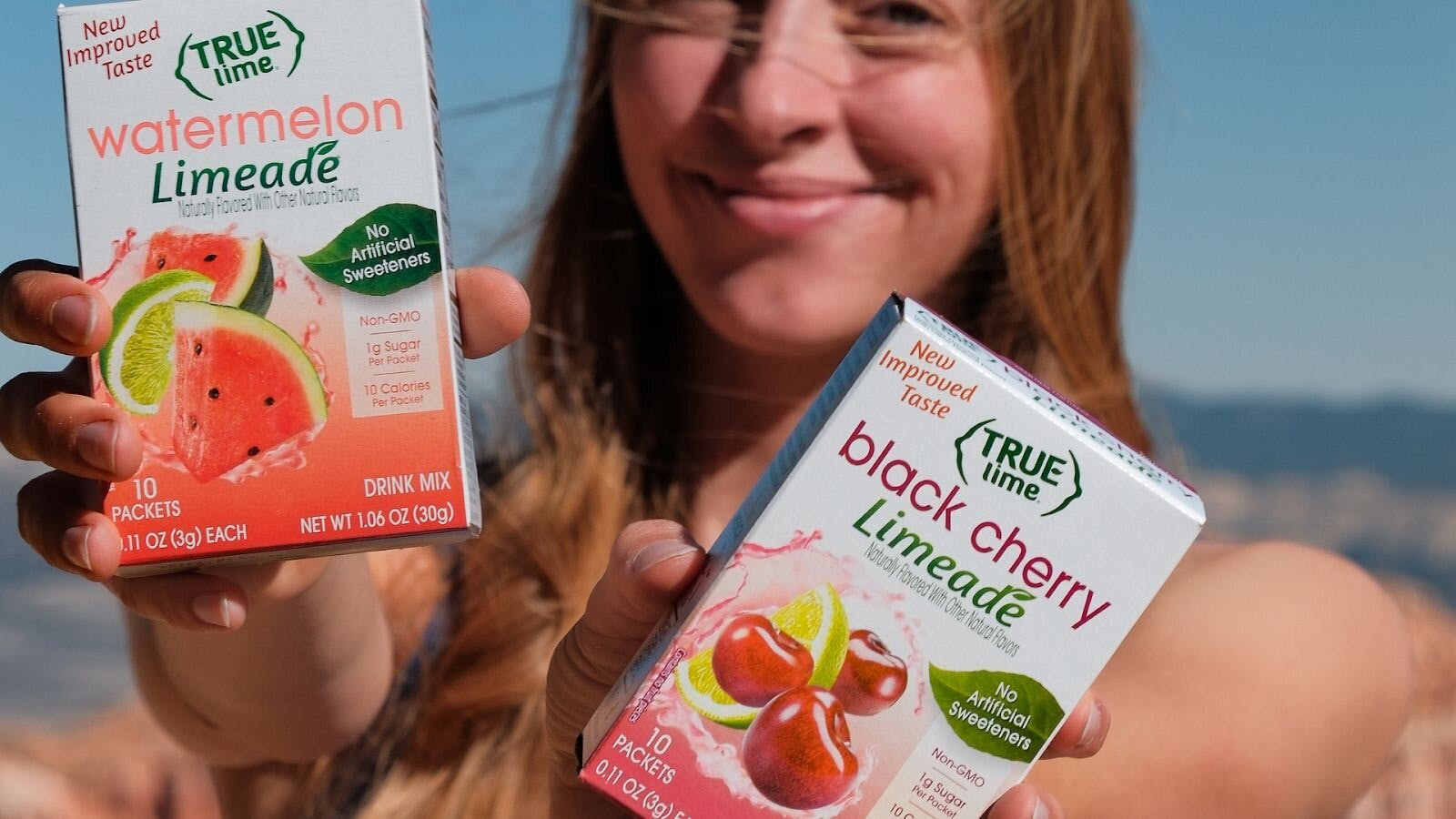 Woman Holding Up True Lime Watermelon Limeade & Black Cherry Limeade